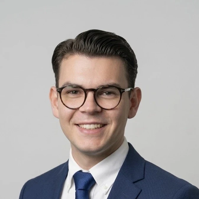 Constantin Bornée mit blauem Anzug, weißem Hemd und Brille vor hellem Hintergrund, Interzero, 2026